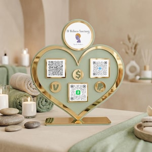 May include: A heart-shaped sign with a gold trim and a light green interior. The sign has a circular top with the text "IV Wellness Sanctuary" and several QR codes and payment logos. The sign is on a table with spa-themed decor.