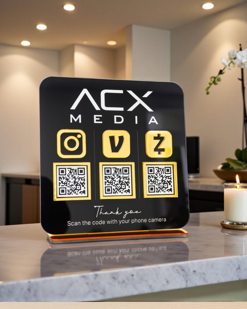 May include: A black sign with the text "ACX MEDIA" and social media icons. Below are QR codes and the text "Thank you. Scan the code with your phone camera."