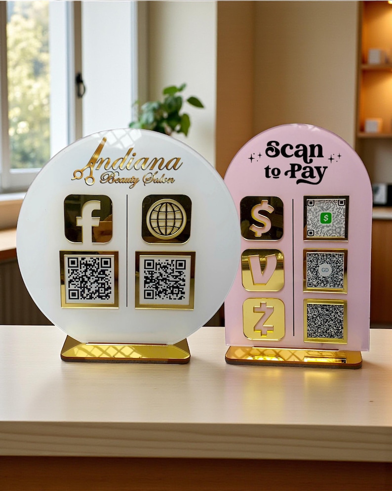 May include: Two decorative signs for a beauty salon. One is white with gold accents, the text "Indiana Beauty Salon", and social media icons. The other is pink with gold accents and the text "Scan to Pay" with payment icons and QR codes.