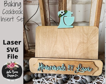 Könnte beinhalten: Ein Holz-Kochbuchständer mit einem Ausschnitt eines türkisfarbenen Küchenroboters mit einem floralen Akzent. Der Ständer hat ein Holzschild mit der Aufschrift "Homemade by Laur" in einer kursivschriftlichen Schrift.