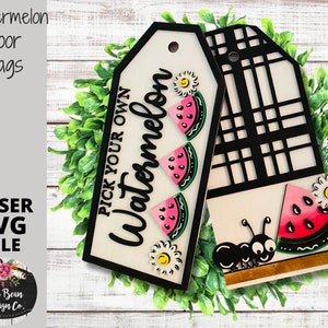Puede incluir: Etiquetas de puerta de madera con temática de sandía. Una etiqueta presenta el texto "PICK YOUR OWN Watermelon" y rodajas de sandía. La otra etiqueta tiene un diseño de celosía negra y una rodaja de sandía con una hormiga.