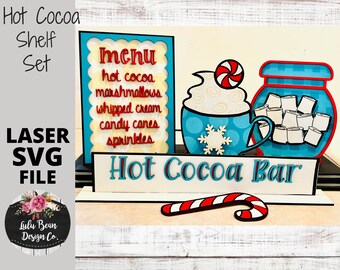 Könnte beinhalten: Ein Holz-Heißgetränke-Bar-Regal-Set mit einer blau-weißen Tasse, einem Marshmallow-Glas, einem Zuckerrohr und einem Schild mit der Aufschrift "Hot Cocoa Bar". Das Schild hat auch eine Speisekarte mit dem Text "menu, hot cocoa, marshmallows, whipped cream, candy canes, sprinkles".
