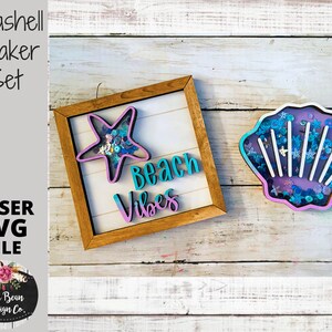 May include: A set of two wooden seashell shaker crafts. The first shaker is a framed square with a blue and pink "Beach Vibes" sign and a turquoise starfish. The second shaker is a seashell with a purple interior and white lines. Both shakers have a variety of colorful sequins inside.