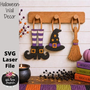 May include: A wooden wall rack with three hanging ornaments: a pair of purple and white striped witch legs with black boots, a black witch hat with yellow stars, and a wooden broomstick. The text reads Halloween Wall Decor and SVG Laser File.