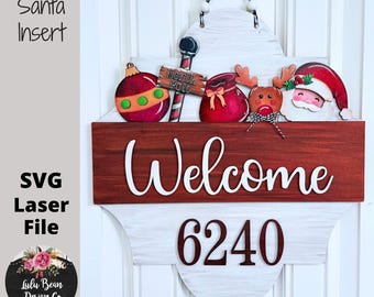 Puede incluir: Un letrero de bienvenida navideño de madera con inserciones intercambiables de Papá Noel. El letrero presenta una combinación de colores rojo y blanco, con la palabra "Welcome" en escritura blanca. Incluye un número de casa y elementos decorativos navideños.