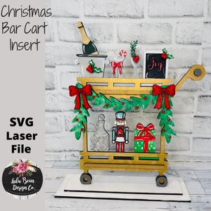 May include: A wooden Christmas bar cart insert with festive decorations. The cart features a champagne bottle, a glass, a gift, and a nutcracker. The cart is decorated with red bows and green garland. The text "Christmas Bar Cart Insert" is visible.