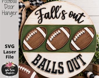 May include: A round wooden door hanger featuring a white background with a horizontal green stripe. Three brown footballs with white laces are centered. The text reads Fall's out and BALLS OUT in black lettering. A buffalo plaid bow is attached at the top.