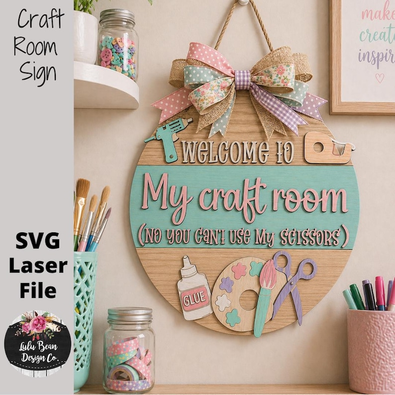 May include: A wooden craft room sign with a light blue and pink color scheme. The sign reads "Welcome to My craft room" and includes a bow, glue bottle, paint palette, and scissors. The sign is decorated with a burlap and floral ribbon.