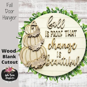 May include: A wooden fall door hanger with a stacked pumpkin design and the words "Fall is proof that change is beautiful." The round sign is surrounded by greenery and includes the text "Wood Blank Cutout."