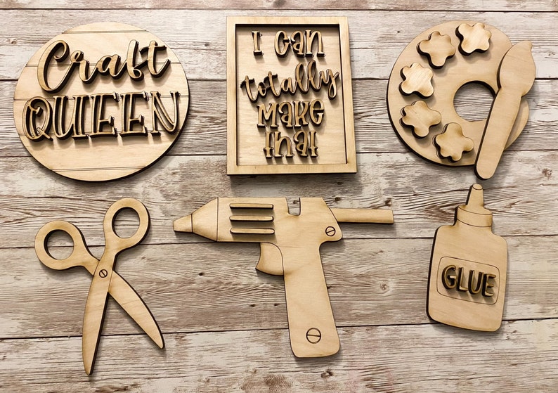 May include: Wooden craft supplies including a paint palette, glue bottle, scissors, glue gun, and signs that say "Craft Queen" and "I can totally make that".