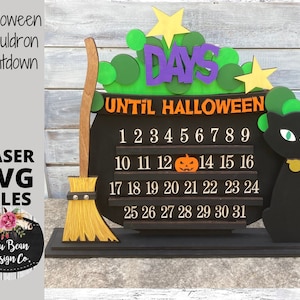 May include: A black cauldron with a countdown calendar for Halloween. The numbers 1 through 31 are displayed on the cauldron. The text "Days Until Halloween" is above the numbers. A black cat with green eyes is on the right side of the cauldron. A broom is on the left side of the cauldron.