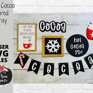 May include: A set of laser cut SVG files for a hot cocoa tiered tray. The design includes a mug of hot cocoa, a snowflake, a sign that says "hot cocoa 25¢", a banner that says "COCOA", and a sign that says "I just want to watch Christmas movies and drink".