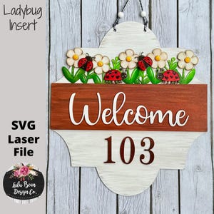 May include: Wooden welcome sign with a white and brown finish, featuring the word "Welcome" in white script and the number "103". The sign is decorated with white flowers, green leaves, and red ladybugs. The text "Ladybug Insert" and "SVG Laser File" are also visible.