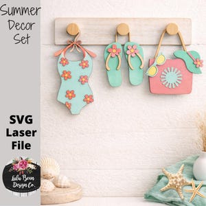 May include: A wooden summer decor set including a swimsuit, flip-flops, and a beach bag with sunglasses and a hat. The swimsuit and flip-flops are light blue with orange flower accents. The beach bag is pink with a light blue sunburst design.