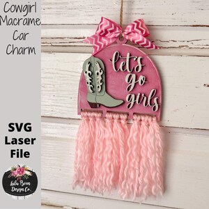 May include: Pink cowgirl-themed macrame car charm with a pink bow, a light green cowboy boot, and the phrase "let's go girls." The charm includes pink fringe and is designed as an SVG laser file.
