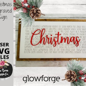 May include: A wooden sign with a red "Christmas" inscription and a white background. The sign features a list of Christmas-themed words and phrases, including "snowballs", "jingle bells", "Santa", and "Donner Falala".