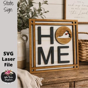 May include: Wooden "HOME" sign with a Virginia state cutout. The sign features a dark frame, black letters, and a light-colored background. The Virginia cutout is on a circular wooden piece. The sign is displayed on a wooden surface.