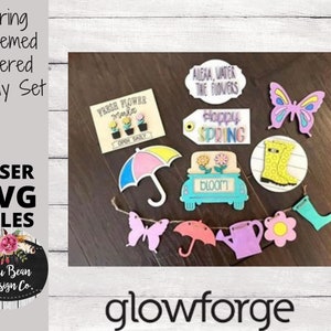 May include: A set of spring-themed tiered tray decor featuring a variety of wooden cutouts. The cutouts include a butterfly, a watering can, a flower, an umbrella, a car with the word "bloom" on it, a pair of wellies, and a sign that says "Happy Spring".