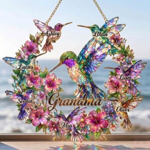 May include: A decorative hummingbird wreath with the word "Grandma" in the center. The wreath features colorful hummingbirds and flowers, with names like "Ashley", "Ethan", "Lucas", "Liam", "Mia", "Oliver", and "Sophia" displayed.