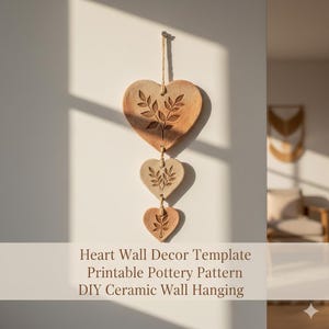 May include: A three-piece heart-shaped wall hanging made of ceramic. Each heart is a different shade of brown and features an embossed botanical design. The hearts are connected by a natural twine and hang against a white wall.