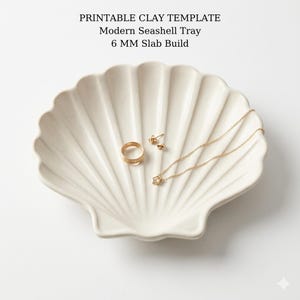 Könnte beinhalten: Eine cremefarbene, muschelförmige Schale mit geripptem Design, die einen goldenen Ring, Ohrringe und eine Halskette enthält. Auf der Schale steht der Text "PRINTABLE CLAY TEMPLATE Modern Seashell Tray 6 MM Slab Build".