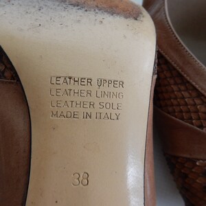 May include: Close-up of the sole of a brown leather shoe with a snakeskin pattern. The shoe is labeled "Leather Upper, Leather Lining, Leather Sole, Made in Italy" and size 38.