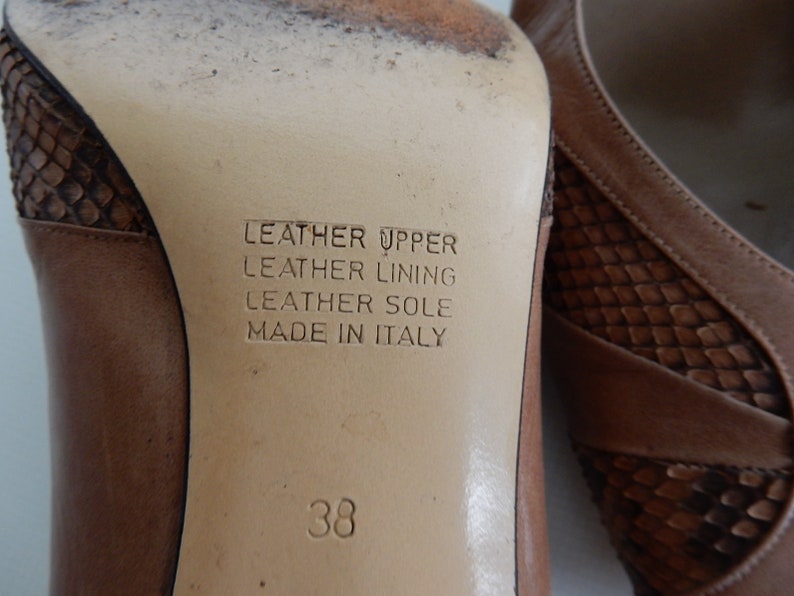 May include: Close-up of the sole of a brown leather shoe with a snakeskin pattern. The shoe is labeled "Leather Upper, Leather Lining, Leather Sole, Made in Italy" and size 38.
