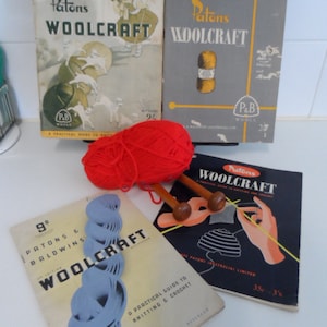 May include: Four vintage Patons Woolcraft knitting books with a ball of red yarn and two knitting needles. The books feature different designs and instructions for knitting and crocheting.