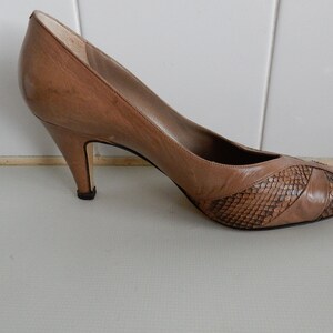 May include: A pair of brown leather pumps with a snakeskin pattern on the toe. The heels are about 3 inches high.