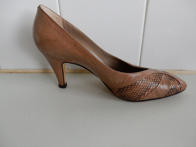 May include: A pair of brown leather pumps with a snakeskin pattern on the toe. The heels are about 3 inches high.