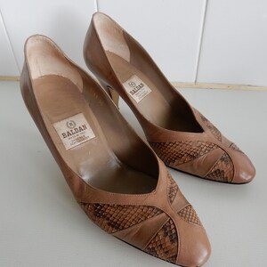 May include: Pair of brown leather heeled shoes with a snakeskin pattern. The shoes have a pointed toe and a low heel. The label on the inside of the shoe reads "Baldan Made in Italy Leather Upper Leather Lining"