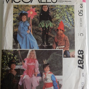 May include: A McCall's sewing pattern for children's costumes. The pattern includes five costumes: a blue fairy, a green fairy, a red and brown gnome, a pink princess, and a blue and red knight. The pattern number is 8787 and the size is extra small.