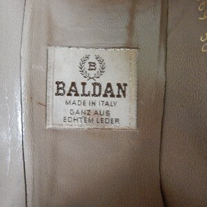 May include: Close-up of a brown leather shoe insole with a white label that reads "Baldan Made in Italy Ganz aus Echtem Leder".