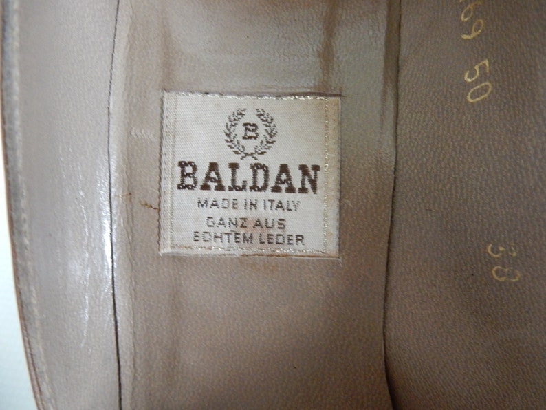 May include: Close-up of a brown leather shoe insole with a white label that reads "Baldan Made in Italy Ganz aus Echtem Leder".