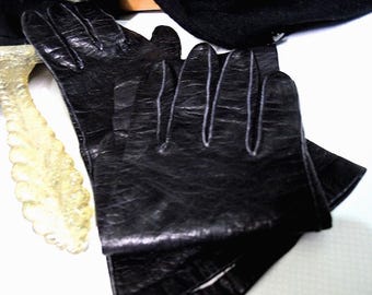 May include: A pair of black leather gloves with a textured finish. The gloves are folded in half and the fingertips are visible.