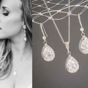 Peut inclure: Un ensemble de bijoux de mariée comprenant un collier et des boucles d'oreilles. L'ensemble comprend un collier chaîne argenté avec un pendentif en forme de goutte et des boucles d'oreilles assorties, ornés de cristaux clairs.