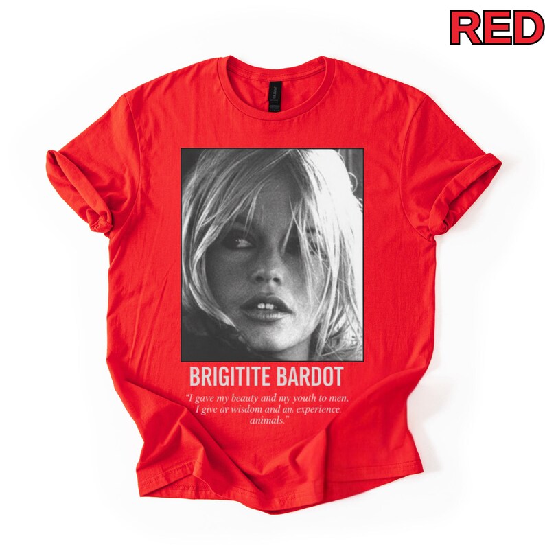 May include: A red t-shirt featuring a black and white portrait of Brigitte Bardot. The text "BRIGITITE BARDOT" is below the image, along with a quote about beauty, youth, wisdom, and animals. The word "RED" is in the top right corner.