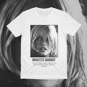 May include: White t-shirt featuring a black and white image of Brigitte Bardot. The image is in a square frame with the name "BRIGITITE BARDOT" below it, along with a quote about beauty, youth, wisdom, and animals.