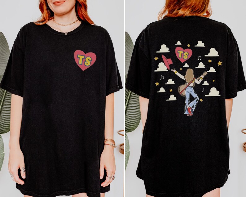 May include: A black t-shirt featuring a small red heart on the front left chest with the yellow letters TS inside. The back displays a graphic of a person with long hair holding a guitar and hat, surrounded by clouds, stars, and a heart with TS.