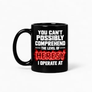 May include: A black ceramic mug featuring white text that reads YOU CAN'T POSSIBLY COMPREHEND THE LEVEL OF, followed by the word HERESY in a glowing red fire effect, and the text I OPERATE AT below it in white, all centred on the front.