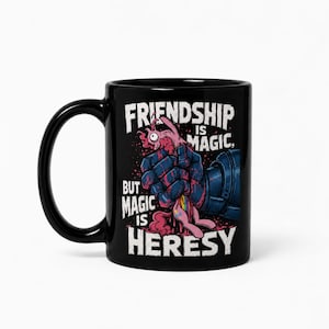 Può includere: Una tazza in ceramica nera con un'illustrazione grafica di un guanto corazzato scuro che schiaccia un pony rosa. Il testo recita: Friendship is magic, but magic is heresy. Il design include schizzi rossi e una coda di pony color arcobaleno.