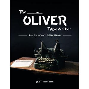 May include: A book cover featuring "The Oliver Typewriter" in white text, with the subtitle "The Standard Visible Writer." An antique typewriter sits on a wooden surface, with a sheet of paper to the left. The author's name, Jett Morton, is at the bottom.