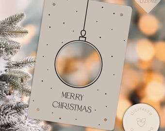 May include: A beige Christmas card with a black line drawing of a bauble and the words "MERRY CHRISTMAS". The card has small black dots scattered around the bauble. A small, round, beige sticker is in the lower right corner.