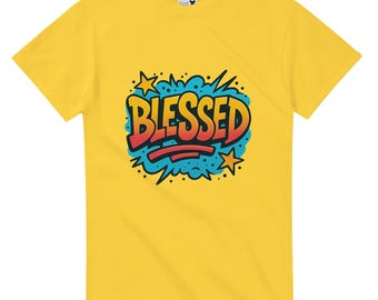 May include: Yellow t-shirt with a colorful graphic that says "BLESSED". The word is in a bold, comic book style font with red and orange letters, outlined in black. The graphic includes blue, yellow, and black accents.