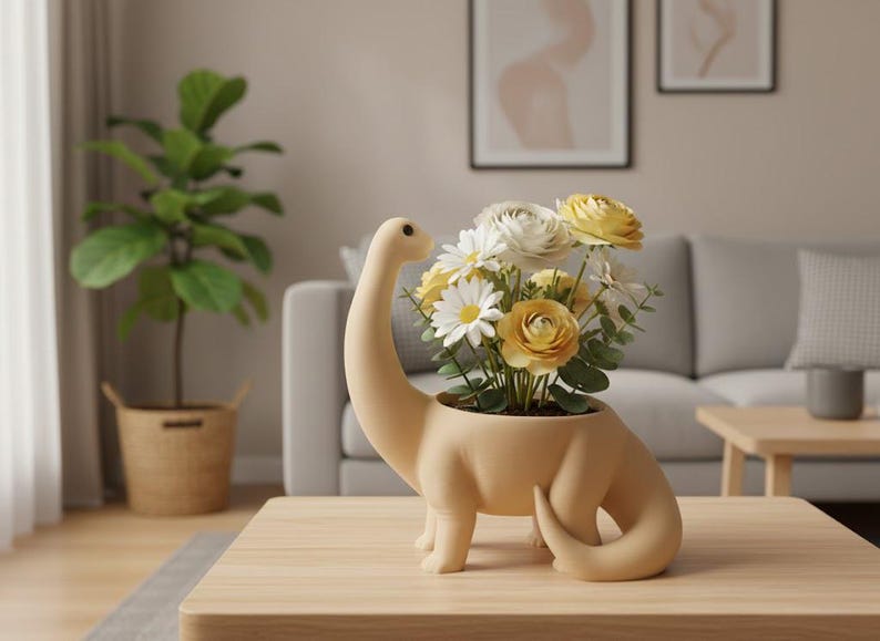 May include: A matte beige ceramic planter shaped like a long-necked dinosaur, filled with a bouquet of white and yellow flowers with green leaves. The dinosaur figure has a smooth, rounded body, a curved neck, and a curled tail, serving as a vessel.