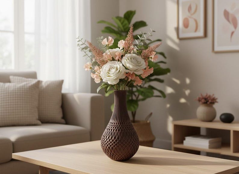 May include: A dark brown vase with a complex, open-work lattice pattern holds a bouquet of white roses, pale peach sweet peas, and feathery pink astilbe stems mixed with green eucalyptus leaves, creating a textured floral arrangement.