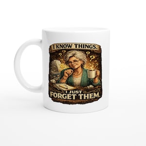 May include: White ceramic mug with a humorous graphic. The design features an illustration of a woman with glasses, a pen, and a coffee cup, with the text "I KNOW THINGS. I JUST FORGET THEM."