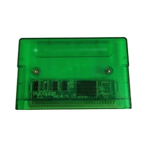 Op de afbeelding: Een transparante groene videogamecartridge. De cartridge heeft een rechthoekige vorm met afgeronde hoeken. De interne componenten zijn zichtbaar door het plastic. De tekst "SMD_MG_TTL_10" is op de printplaat gedrukt.