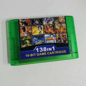 Op de afbeelding: Een groene 16-bit game cartridge met een kleurrijk label met verschillende game covers, waaronder Sonic en Dragon Ball Z. Het label leest "138 in 1" en "16-BIT GAME CARTRIDGE".