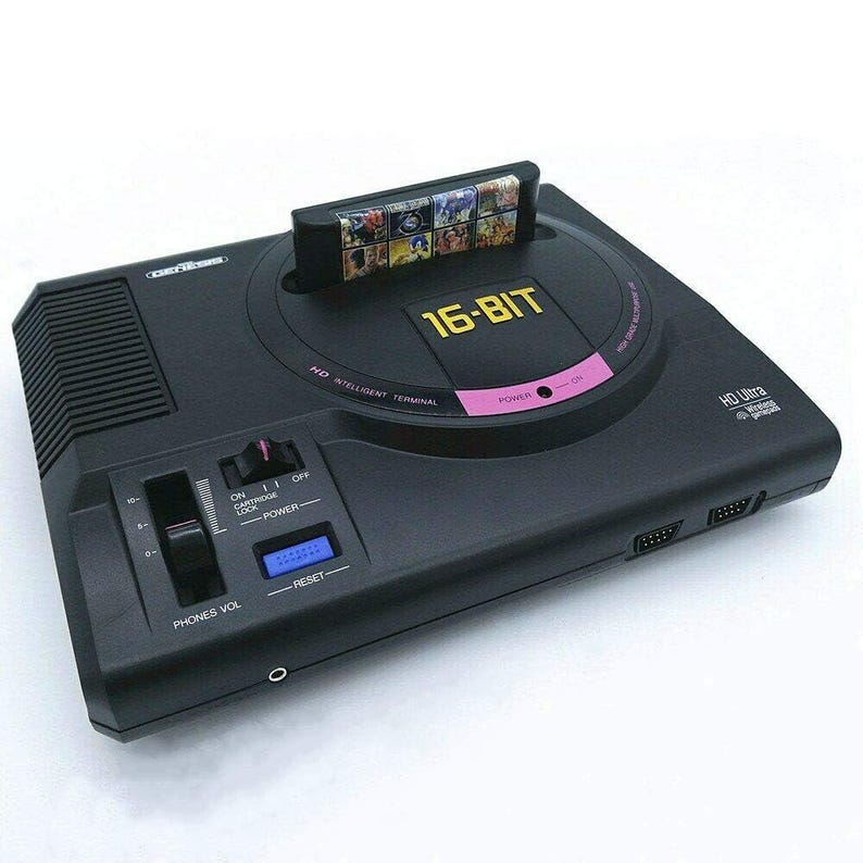 Op de afbeelding: Zwarte 16-bit videogameconsole met een spelcartridge erin. De console heeft een roze accent en de tekst "16-BIT" in goud. Het heeft een volumeregeling, een aan/uit-knop en een resetknop. De console is gemarkeerd met "HD Ultra".